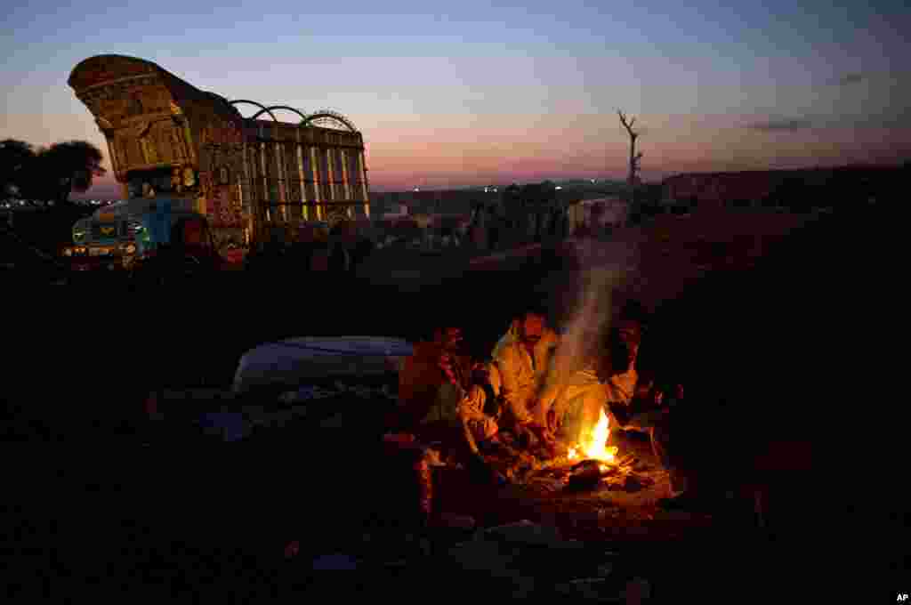 Pakistani vendors sit around a fire to keep themselves warm in a livestock market set up for the Eid al-Adha festival in Islamabad, Pakistan, October 25, 2012. 