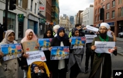 Chairman of the London Fatwa Council, Mohammad Yazdani Raza, right, holds a sign as he marches with others near Borough Market in London, Sunday, June 4, 2017.