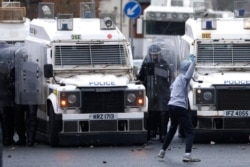 A Nationalist youth prepares to throw a projectile at a police line blocking a road near the Peace Wall in West Belfast, Northern Ireland, April 8, 2021.