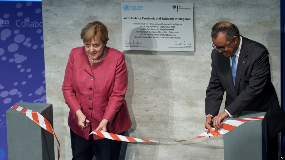 Dirjen WHO Tedros Adhanom Ghebreyesus, kanan, dan Kanselir Jerman Angela Merkel memotong pita upacara pada peresmian "Pusat untuk Intelijen Pandemi dan Epidemi' di Berlin, Jerman, 1 September 2021. (Foto: AP)