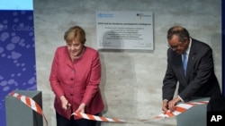 World Health Organization chief Tedros Adhanom Ghebreyesus, right, and German Chancellor Angela Merkel cut the ceremonial ribbon at the inauguration of the "WHO Hub for Pandemic and Epidemic Intelligence,' in Berlin, Germany, Sept. 1, 2021. 