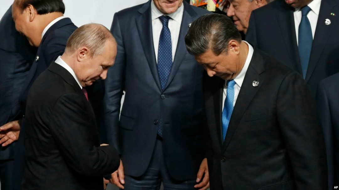 Presiden Rusia Vladimir Putin (kiri) dan Presiden China Xi Jinping bersiap untuk foto bersama di KTT G20 di Osaka, Jepang, Jumat, 28 Juni 2019.(Foto: Kim Kyung-Hoon/Pool Photo via AP)