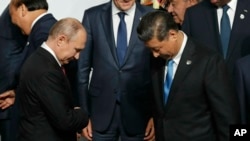 Presiden Rusia Vladimir Putin (kiri) dan Presiden China Xi Jinping bersiap untuk foto bersama di KTT G20 di Osaka, Jepang, Jumat, 28 Juni 2019.(Foto: Kim Kyung-Hoon/Pool Photo via AP)