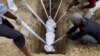 A body of a woman who died from the coronavirus disease (COVID-19), is lowered into the ground during her funeral at a graveyard in New Delhi, India.