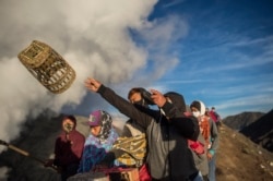 Suku Tengger melempar sesajen ke kawah gunung berapi Gunung Bromo di Probolinggo, Jawa Timur pada 26 Juni 2021, selama festival Yadnya Kasada untuk mencari berkah dari dewa dengan mempersembahkan sesaji beras, buah, ternak dan barang-barang lainnya. (Foto