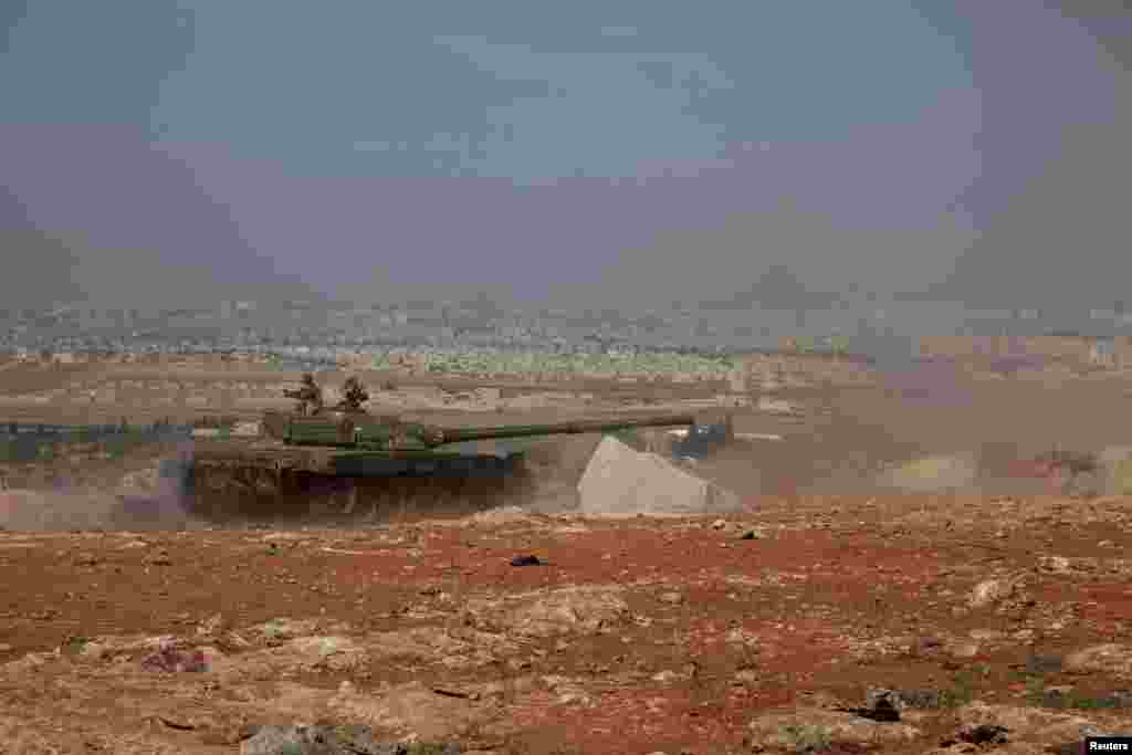 Syrian army tanks loyal to President Bashar al-Assad advance toward the Handarat camp, near Aleppo, May 21, 2014.