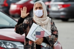 FILE - Aisha Kazman Kammawie, of Ankeny, Iowa, takes the oath of allegiance during a drive-thru naturalization ceremony at Principal Park in Des Moines, Iowa.