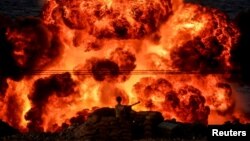 An explosion is seen behind a soldier during a joint exercise called the 'Great Prophet 17', in the southwest of Iran, in this picture obtained on Dec. 22, 2021.