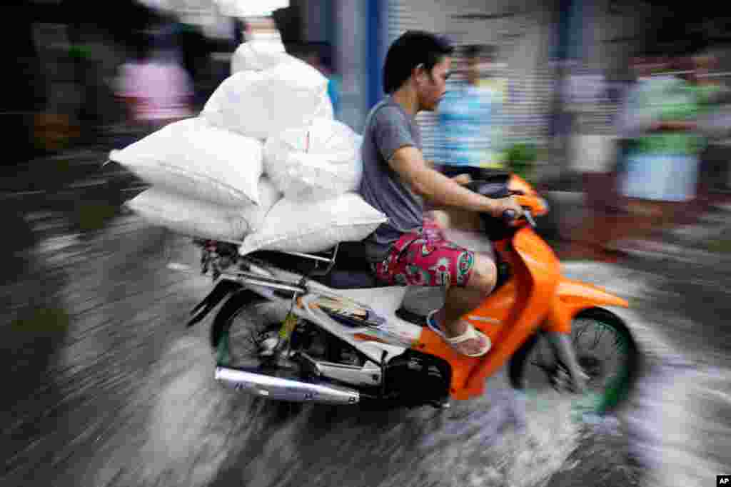 October 28: A man rides his motorcycle through flooded streets to deliver goods in Bangkok, Thailand. (AP Photo/Aaron Favila)