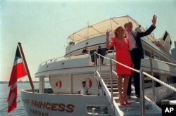 FILE - Real estate developer Donald Trump waves to reporters with his wife, Ivana, as they board their luxury yacht The Trump Princess in New York City, July 4, 1988.