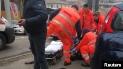 Health care personnel help an injured person after being wounded by gunfire from a vehicle in Macerata, Italy, Feb. 3, 2018. 