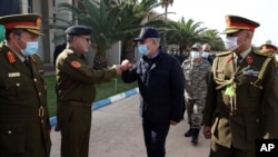 FILE - Turkey's Defense Minister Hulusi Akar, center, and other top Turkish military commanders, rear, greet Libyan commanders, in Tripoli, Libya, Dec. 26, 2020.