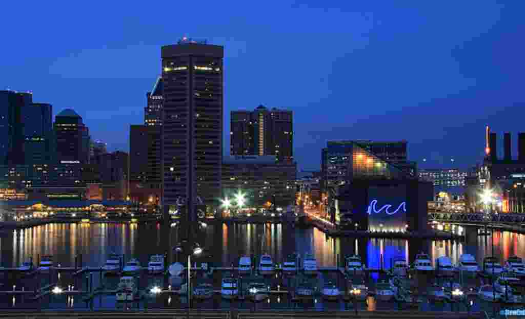 Baltimore’s downtown showplace, the Inner Harbor. The neon “wave”design marks the National Aquarium, one of the major attractions. The tall building to its left is Baltimore’s pentagonal shaped World Trade Center. © Steve Ember