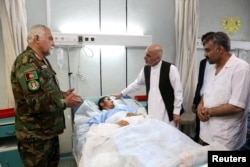 Afghanistan's President Ashraf Ghani visits a victim wounded in April 21's attack on an army headquarters, in Mazar-i-Sharif, April 22, 2017.