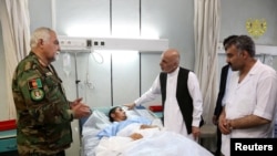 Afghanistan's President Ashraf Ghani visits a victim wounded in April 21's attack on an army headquarters, in Mazar-i-Sharif, April 22, 2017.