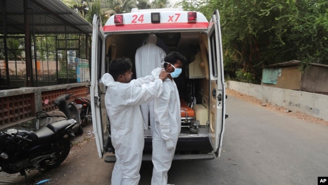 In this file photo, Izhaar Hussain Shaikh, right, an ambulance driver who works for HelpNow, an initiative to help the stretched services of first responders, is assisted by his helper to wear the face mask before picking up a COVID-19 patient in Mumbai, India May 28. (AP)