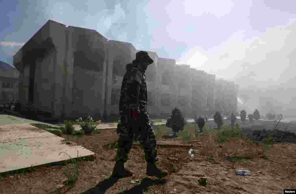 An Afghan security officer walks in front of a government building after an attack by insurgents, Panjshir, Afghanistan,&nbsp;May 29, 2013. 