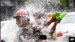 FILE - People riding on a motorbike react as a boy splashes water on them during traditional Thai New Year celebrations or Songkran water festival in Bangkok, April 13, 2015. 