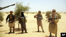 Ansar Dine Islamist fighters stand guard during a hostage handover in the desert outside Timbuktu, Mali, April 24, 2012.