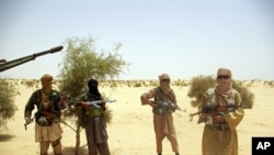 An April 24, 2012 photo shows Ansar Dine Islamist fighters standing guard during a hostage handover in the desert outside Timbuktu, Mali.