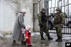 FILE - A woman accompanies her child to be evacuated from Avdiivka to Sviatohirsk, a town about 140 kilometers (88 miles) away and far from the conflict front line, in eastern Ukraine, Feb. 5, 2017.