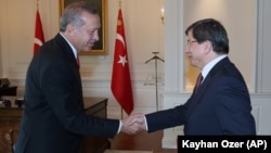 FILE - Turkish President Recep Tayyip Erdogan, left, and Prime Minister Ahmet Davutoglu shake hands, in Ankara, Turkey.