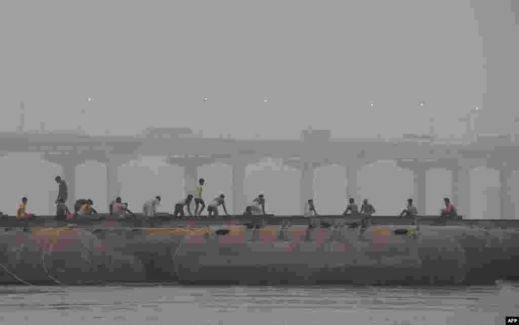 Indian laborers build a floating pontoon bridge over the River Ganges for the upcoming Magh Mela festival in Allahabad.