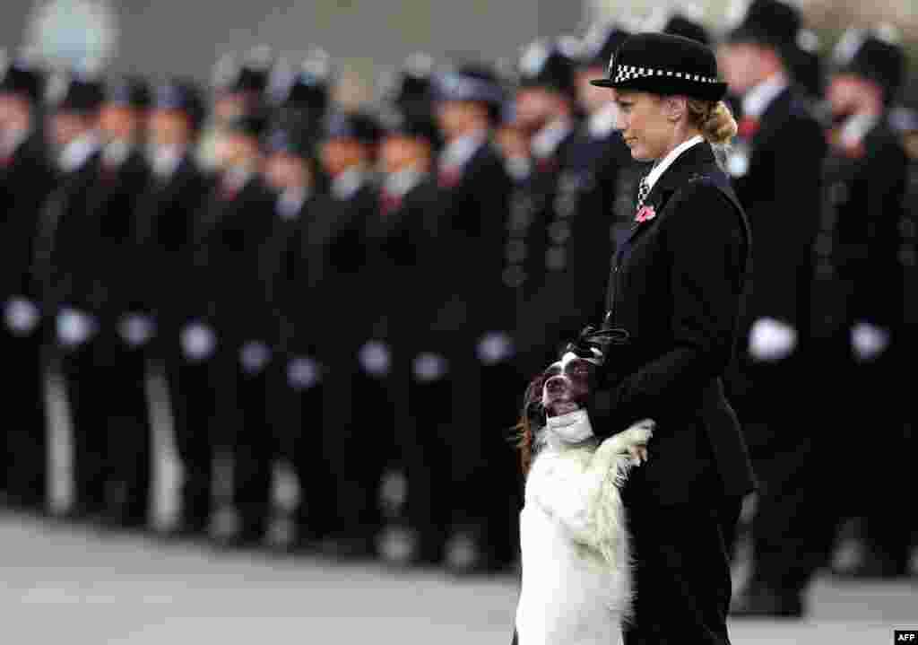 A police officer and her police dog stand at attention at the Metropolitan Police parade to mark the graduation of 182 new recruits from the Metropolitan Police Academy, at Hendon, northwest London.