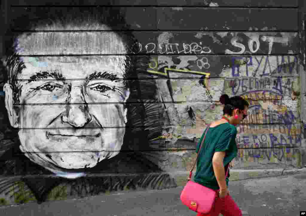 A woman walks past graffiti on a wall that shows late actor Robin Williams after he was found dead at his home in California, in Belgrade, Serbia, Aug. 13, 2014.