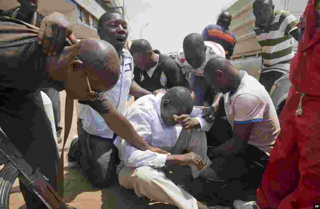 Ugandan opposition leader and presidential candidate Kizza Besigye, center, is surrounded by his bodyguards after being overcome by tear gas fired at them by riot police, as they attempted to walk along a street in downtown Kampala, Uganda. Riot police arrested Besigye and later released him.