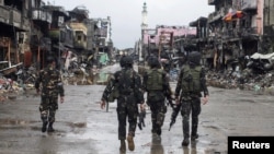 Pasukan pemerintah melewati bangunan dan rumah yang hancur di Datu Sa Dansalan di kota Marawi, Filipina selatan, 17 Oktober 2017.