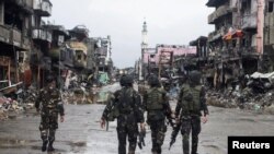 Tentara pemerintah melewati gedung-gedung dan bangunan yang hancur di Datu Sa Dansalan di Kota Marawi, selatan Filipina, 17 Oktober 2017.