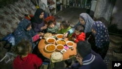 Sebuah keluarga Palestina menikmati Iftar, makanan berbuka puasa, selama bulan Ramadan di apartemen mereka yang rusak di Jabaliya, Jalur Gaza utara (foto: ilustrasi). 