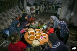 Fatima Al-Absi, kiri, berbuka puasa bersama putri dan cucunya pada hari pertama Ramadan di apartemen mereka yang rusak di Jabaliya, Jalur Gaza utara, 1 Maret 2025. (Foto: AP)