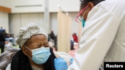 Juanta J. Gordon, left, receives the Moderna coronavirus vaccine from her daughter, nurse Zyra D. Gordon Smith, at Trinity United Church of Christ in Chicago, Illinois, Feb. 13, 2021.