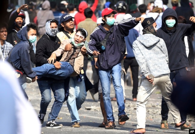 Para pengunjuk rasa menggendong seorang pria yang terluka dalam unjuk rasa menentang hasil pemilu presiden, di Jakarta, 22 Mei 2019.