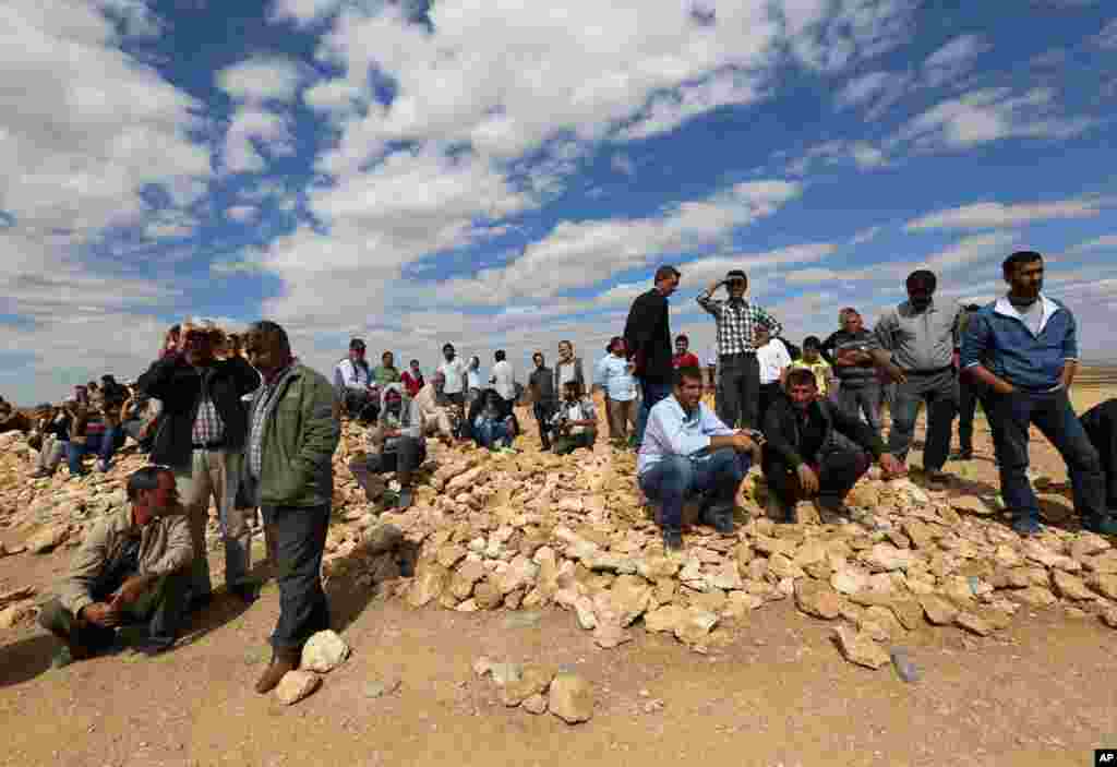 Turkish Kurds watch the fighting between Islamic militants and Kurdish forces to the west of Kobani, Syria, at the Turkey-Syria border near Suruc, Turkey, Sept. 30, 2014.