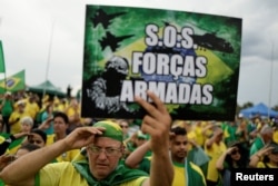 A man holds a sign that reads "SOS Armed Forces" during a protest held by supporters of Jair Bolsonaro at the Army Headquarters in Brasilia, Brazil, November 7, 2022.