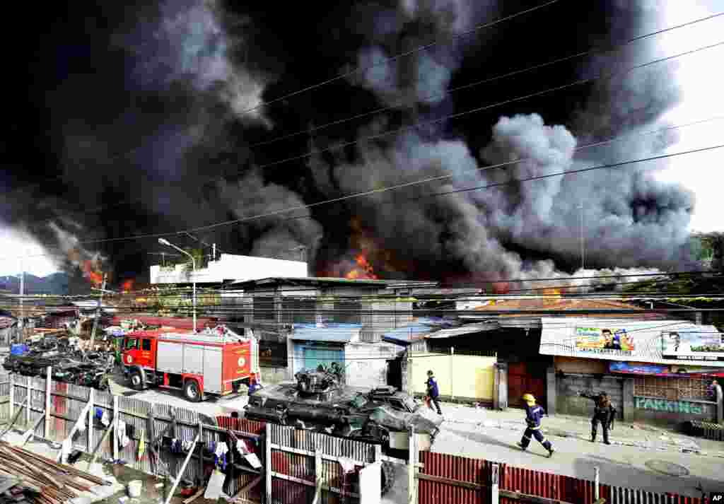 Firemen rush to put out a fire that razed several homes as government troopers continue their assault on Muslim rebels in Zamboanga, Philippines, Sept. 12, 2013.