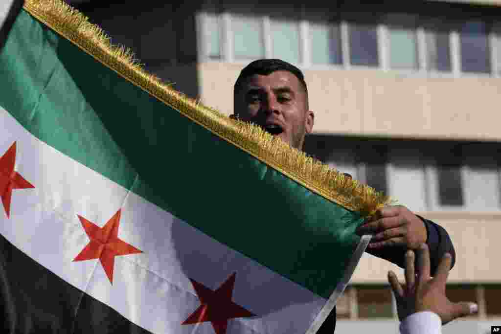 Un hombre sirio ondea una bandera durante una manifestación espontánea para celebrar la caída del régimen de Assad, en Nicosia, Chipre, el domingo 8 de diciembre de 2024. (Foto AP/Petros Karadjias)