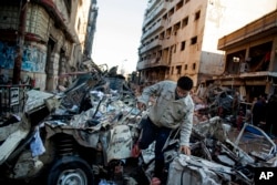 An Egyptian man makes his way through rubble at the scene of an explosion at a police headquarters building in the Nile Delta city of Mansoura, Egypt, Dec. 24, 2013.