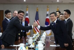 FILE - U.S. Defense Secretary Mark Esper clasps hands with South Korean Defense Minister Jeong Kyeong-doo during their meeting in Seoul, South Korea, Aug. 9, 2019.