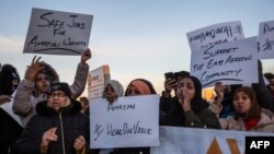 Les manifestants scandent des slogans et tiennent des pancartes lors d'une manifestation au centre de traitement des commandes Amazon à Shakopee, dans le Minnesota, le 14 décembre 2018.