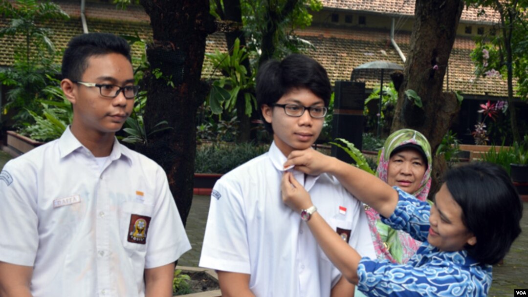 Pauline Arifin dari Komisi Pemberantasan Korupsi (KPK) memasangkan pin "Jujur Itu Hebat" untuk Muhammad Tasqif Wismadi, siswa SMA Negeri 3 Yogyakarta, disaksikan Kepala Sekolah (belakang) dan teman Tsaqif. (Foto: VOA/Munarsih Sahana)