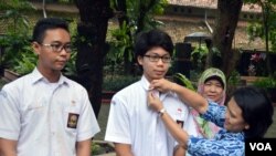 Pauline Arifin dari Komisi Pemberantasan Korupsi (KPK) memasangkan pin "Jujur Itu Hebat" untuk Muhammad Tasqif Wismadi, siswa SMA Negeri 3 Yogyakarta, disaksikan Kepala Sekolah (belakang) dan teman Tsaqif. (Foto: VOA/Munarsih Sahana)