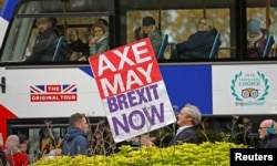 A pro-Brexit campaigner holds a placard as a tourist bus passes by in Westminster London, Britain, Nov. 16, 2018.