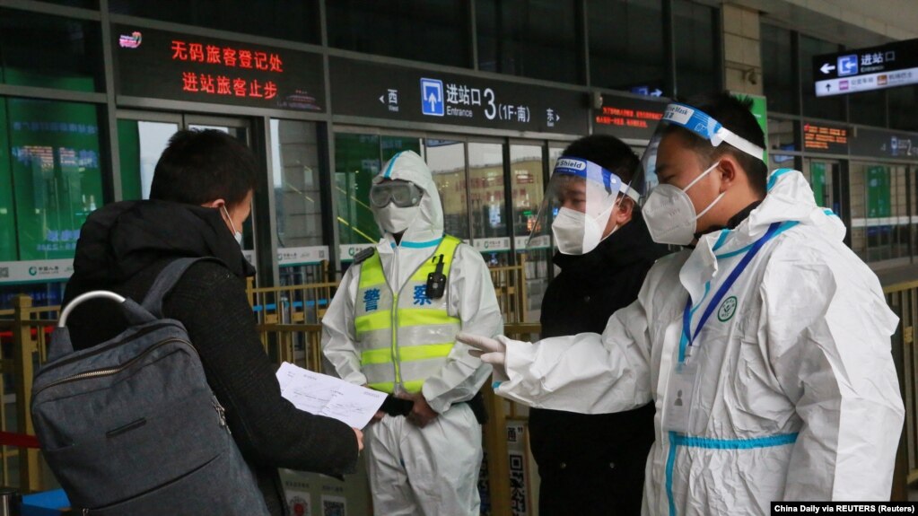12月23日，警察和防疫人员在西安火车站检查旅客的文件。(photo:VOA)