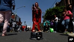 In this March 1, 2017 photo, a Death Saint or "Santa Muerte" statuette stands in the middle of the road, placed there by its owner who waits for people to offer it things like food, tobacco and alcohol, in Mexico City's Tepito neighborhood.