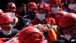 Medics and rescue personnel carry an injured person from the debris of a collapsed building in Izmir, Turkey, Oct. 31, 2020. 