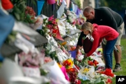 Mourners lay flowers on a wall at the Botanical Gardens in Christchurch, New Zealand, March 16, 2019. New Zealand's stricken residents reached out to Muslims in their neighborhoods and around the country Saturday, in a fierce determination to show kindness to a community in pain.